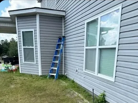 Bare, patchy strip of ground along the side of a house before the bed was installed